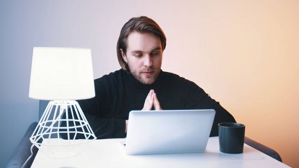 Молодий кавказький чоловік має відеоконференцію на ноутбуці в своїй квартирі
 - Фото, зображення
