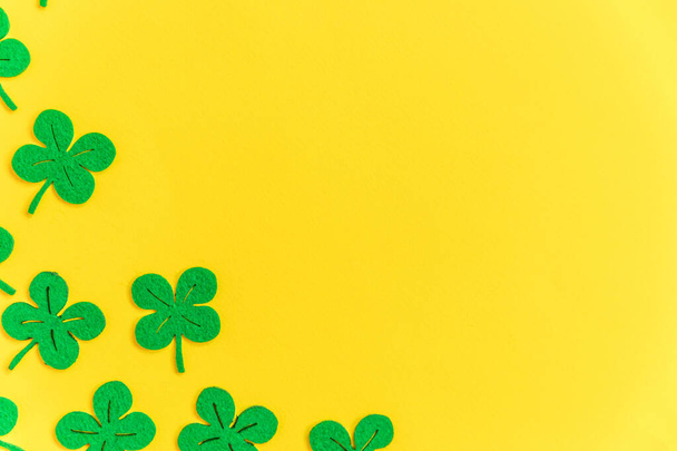 St Patricks Day background. Simply minimal design with green shamrock. Clover leaves isolated on yellow background. Symbol of Ireland. Lucky fortune wish concept. Flat lay top view layout copy space - Photo, Image