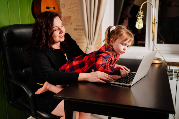 the little daughter prevents the freelancer mother from working on the computer. - Photo, Image