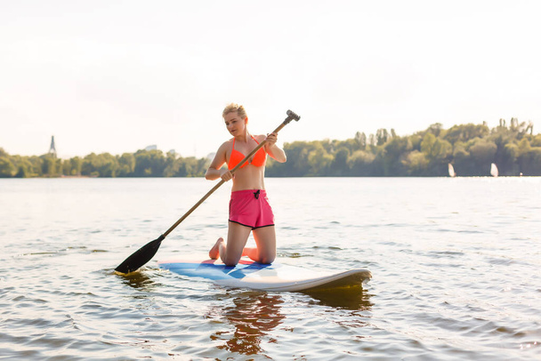 Mujer atractiva joven en stand up paddle board en el lago, SUP - Foto, Imagen