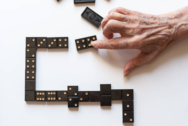 Family entertainment for a fun leisure game of dominoes. The hand of an elderly woman puts a domino on the table. - Φωτογραφία, εικόνα