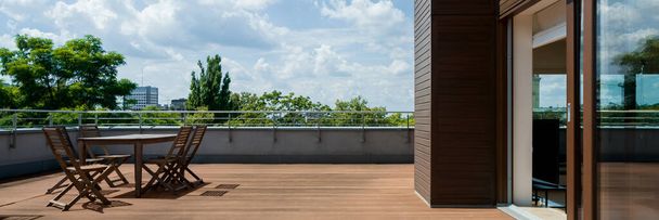 Panorama of spacious terrace with wooden floor and furniture, and amazing view - 写真・画像