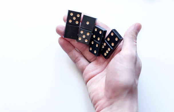Family entertainment for a fun leisure game of dominoes. The young man's hand holds a domino in his hands - Foto, Bild