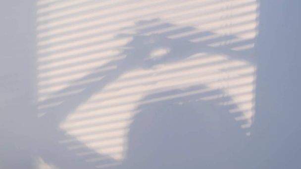 Stíny na stěně z okna zataženého žaluziemi a siluetou žen. Rozmazané tmavé stíny pohybující se po stěně. - Fotografie, Obrázek