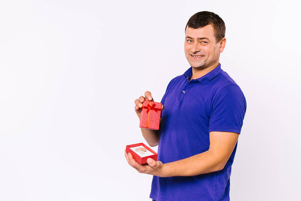 A satisfied deaf man received a hearing aid in a red gift box as a present. White background and empty sidewall space. - Φωτογραφία, εικόνα