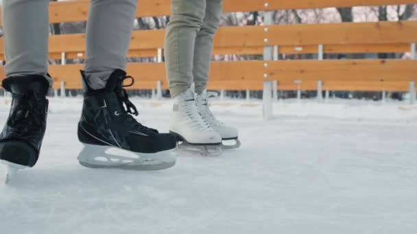 Alacsony szakaszú közelkép három pár felismerhetetlen lábról korcsolyát viselve, amelyek télen szabadtéri jégpályán mozognak. - Felvétel, videó