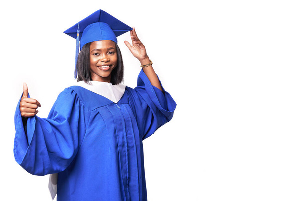 African-American beautiful woman in a blue robe and hat, on a white isolated background smiles and shows thumb up - Photo, Image