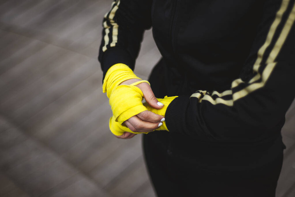 Primer plano de ajuste, mujer poniendo envolturas de boxeo, vendaje en sus manos. - Foto, Imagen