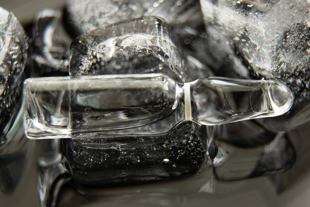 vakcina ampulla fekszik jég egy fekete háttér közelkép, vakcinázás - Fotó, kép