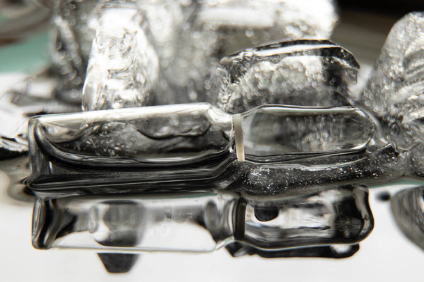 vaccinampul ligt in het ijs op een zwarte achtergrond close-up, vaccinatie - Foto, afbeelding