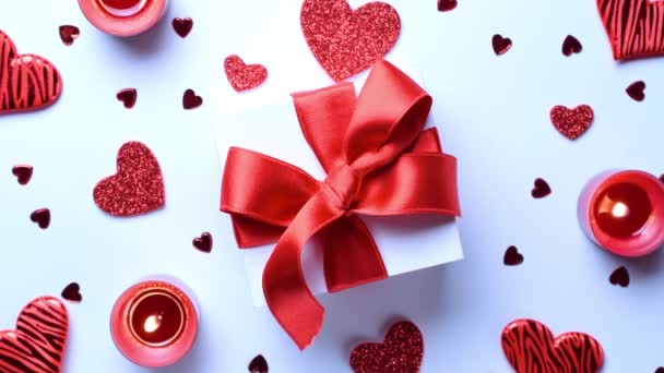 Χαρούμενες μέρες. Κόκκινες καρδιές αγάπης, ρομαντικό κουτί δώρου, κερί ημέρας του Αγίου Βαλεντίνου σε λευκό τραπέζι. Ρομαντικό πρότυπο μηνύματος με χώρο αντιγραφής. Στο Top View. Άποψη από ψηλά - Πλάνα, βίντεο