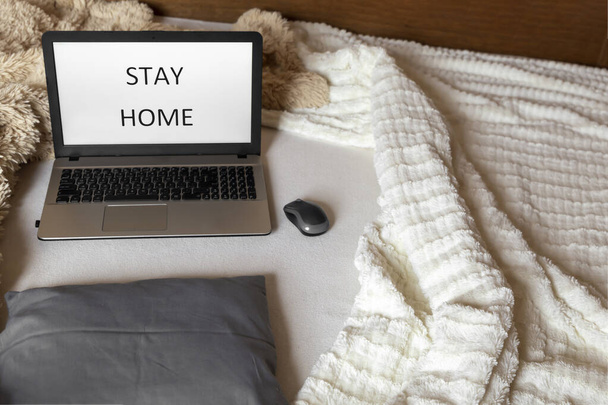 Laptop on the bed with "stay home" written on the screen. Cozy home concept. Work from home - Fotografie, Obrázek