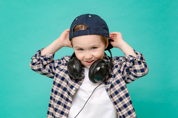野球帽の中の面白い5歳の少年は音楽に夢中です。緑の背景に隔離されています。スペースバーをコピーします。音楽好き. - 写真・画像