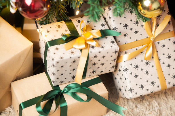 Beautiful Christmas gift boxes on floor near fir tree in room  - Foto, Bild