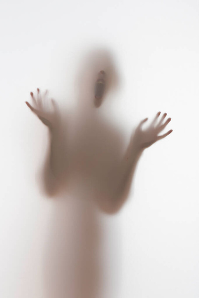 Scary diffuse human face and hands silhouette shouting behind a curtain - Foto, imagen