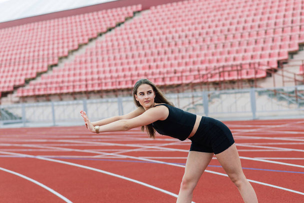 Jovem, bela menina atleta em sportswear está treinando e correndo, esticando-se no estádio - Foto, Imagem