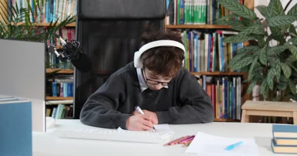 Egy okos kisfiú videóbeszélgetésre használja a számítógépet a tanárával. E-oktatás távoktatás, otthoni oktatás, kovid. Oktatás tanulás online koncepció, tinédzser diák visel fejhallgató segítségével számítógépes tanulás online - Felvétel, videó