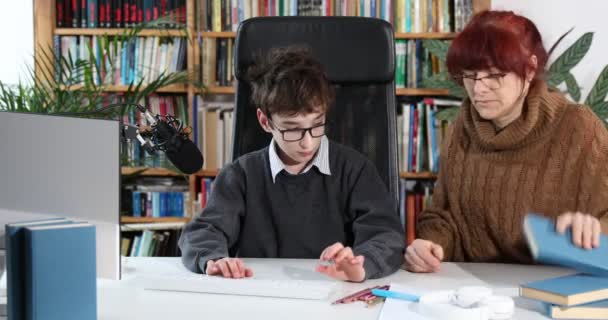 cute boy and mother do homework at home, mom helping son, telling how to do homework. concept education, learning, study. schoolboy in quarantine. a caring mother with glasses helps the boy to do homework at home on the computer - Footage, Video