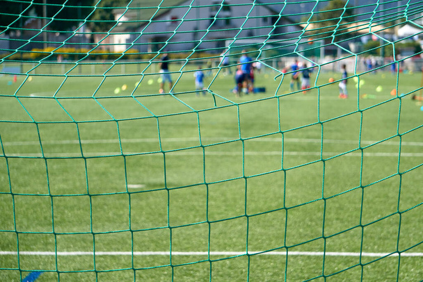 Detaillierte Ansicht eines Tornetzes auf einem Fußballplatz WIth Gruppe von Kindern Training im Hintergrund - Foto, Bild