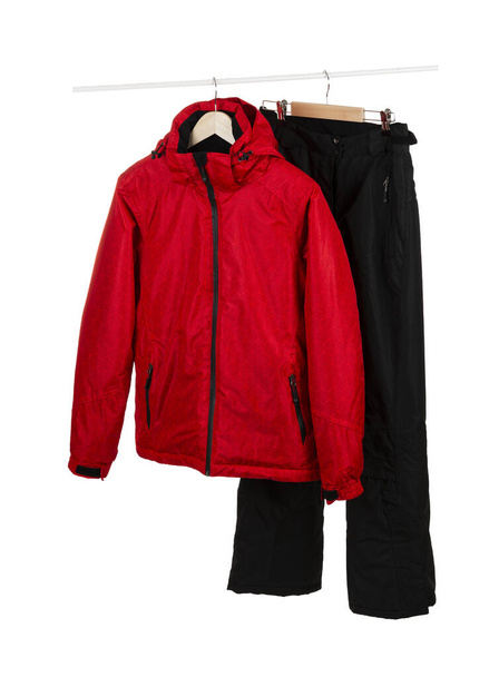 Giacca rossa impermeabile e antivento da sci e pantaloni neri su appendini isolati su sfondo bianco. - Foto, immagini