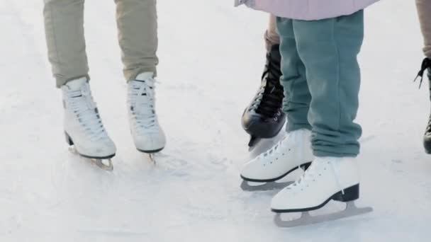 Низкочастотные панорамные кадры мужских и женских ног в фигурном и хоккейном коньках на катке - Кадры, видео