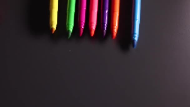 Luminosi marcatori multicolori rotolano su sfondo nero. Arte, dolore, scrittura, cancelleria, feltro. Filmati FullHD di alta qualità - Filmati, video