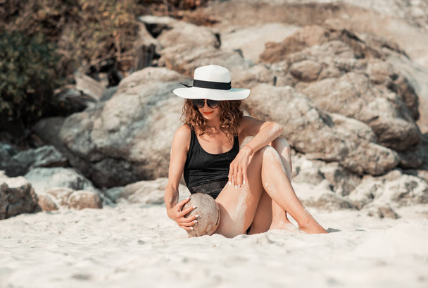 Vonzó divatos nő szórakozás a strandon kókuszdióval - Fotó, kép