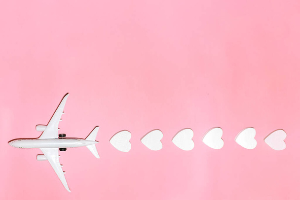 Feliz Dia dos Namorados. Avião branco de passageiros com corações em fundo rosa. Flat lay férias planejando e viajando férias. Conceito de viagem de férias. Vista superior - Foto, Imagem