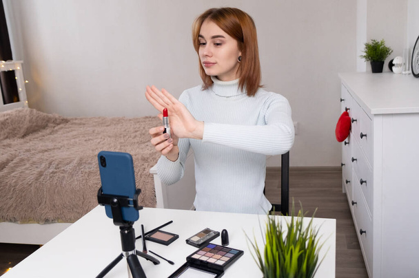 Un beauty blogger ospita un home stream. Makeup artist filma allenamenti online al telefono dalla sua camera da letto. Trucco per te stesso dal video. - Foto, immagini