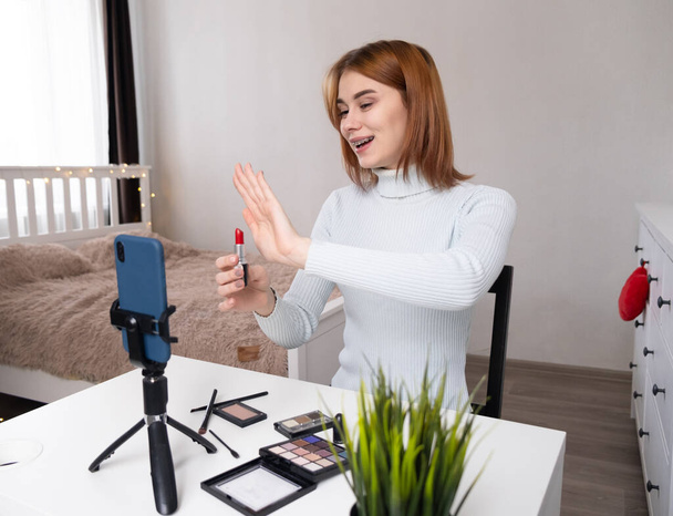 Un blogueur beauté héberge un flux de la maison. Makeup artist filme des séances d'entraînement en ligne au téléphone depuis sa chambre. Maquillage pour vous-même par vidéo. - Photo, image
