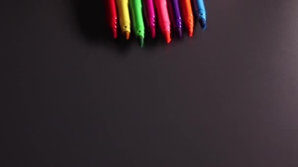 Luminosi marcatori multicolori rotolano su sfondo nero. Arte, dolore, scrittura, cancelleria, feltro. Filmati FullHD di alta qualità - Filmati, video