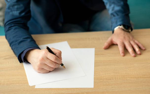 Liikemies toimistossa kirjoittaa kirjeen tai allekirjoittaa asiakirjan pala valkoista paperia mustekynällä kärki. lähikuva pukuisen liikemiehen käsistä - Valokuva, kuva