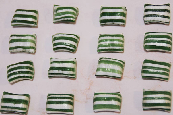 Dulces de menta dispuestos en fila, dulces verdes, dulces de rayas blancas y verdes - Foto, imagen
