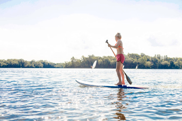 Action Shot of Young Woman on Paddle Board - Photo, Image