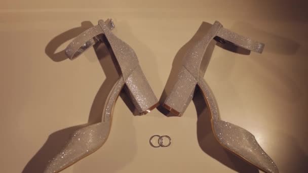 Όμορφες γυναίκες κρεμ χρώμα παπούτσια βράδυ βρίσκονται στο πάτωμα με δύο χρυσά δαχτυλίδια γάμου close-up - Πλάνα, βίντεο