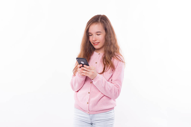 Foto di scuola ragazza utilizzando smartphone su sfondo bianco - Foto, immagini