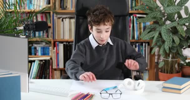 Egy okos kisfiú videóbeszélgetésre használja a számítógépet a tanárával. E-oktatás távoktatás, otthoni oktatás, kovid. Oktatás tanulás online koncepció, tinédzser diák visel fejhallgató segítségével számítógépes tanulás online - Felvétel, videó