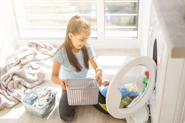 Красива дівчинка-помічник розважається і грає під час прання вдома
. - Фото, зображення