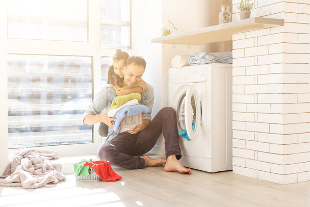 Onnellinen perheen mies isä perheenomistaja ja lapsi tytär pyykissä pesukoneella - Valokuva, kuva