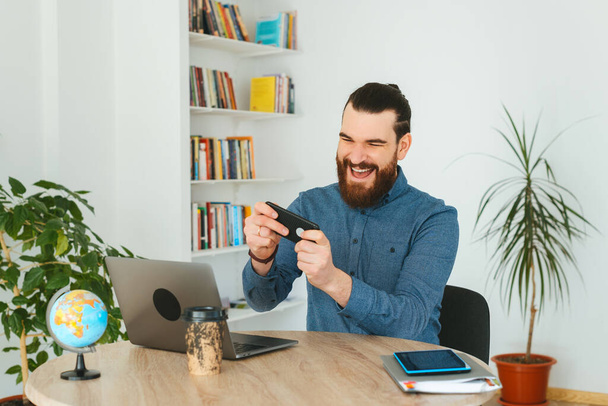 Foto do homem de escritório jogando jogos no smartphone no trabalho - Foto, Imagem
