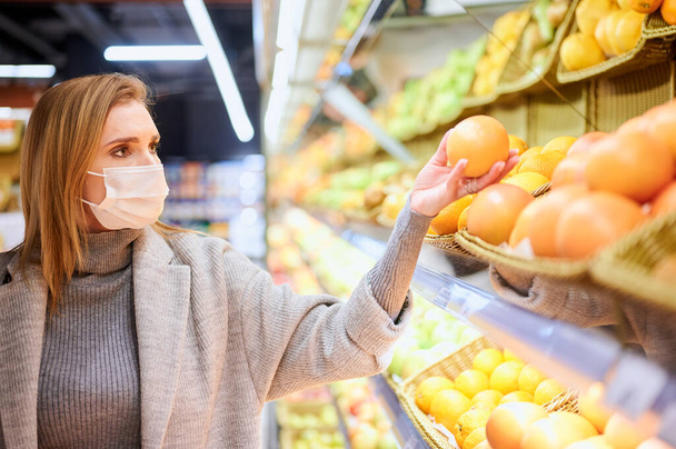 Γυναίκα με ιατρικές μάσκες ψωνίζει στο μπακάλικο κατά τη διάρκεια πανδημίας ιών - Φωτογραφία, εικόνα