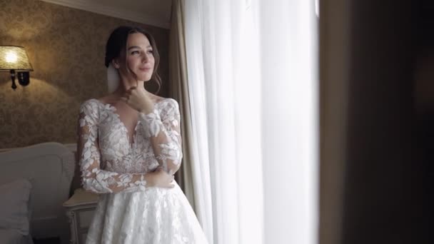 Νύφη σε μπουντουάρ φόρεμα κοντά στο παράθυρο. Πρωινές ετοιμασίες γάμου. Γυναίκα με νυχτικό και πέπλο - Πλάνα, βίντεο