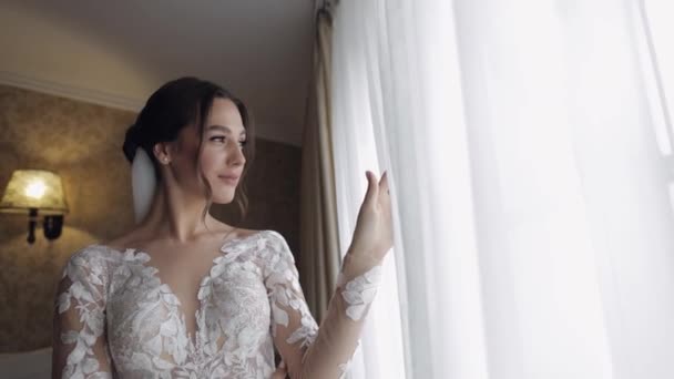 Menyasszony boudoir ruha mellett ablak. Esküvői előkészületek. Nő hálóingben és fátyolban - Felvétel, videó