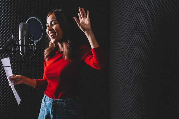 Güzel Asyalı kadın şarkıcı, stüdyo mikrofonu ve pop kalkanını kullanarak şarkı kaydediyor. Müzik sektöründe performans ve gösteri. Kopyalama alanı olan resim. - Fotoğraf, Görsel