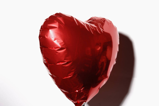 A heart inflated with helium flies on a string on a white background. A gift for Valentines Day. - Zdjęcie, obraz