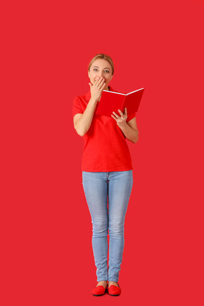Surprised mature woman with book on color background - Photo, image