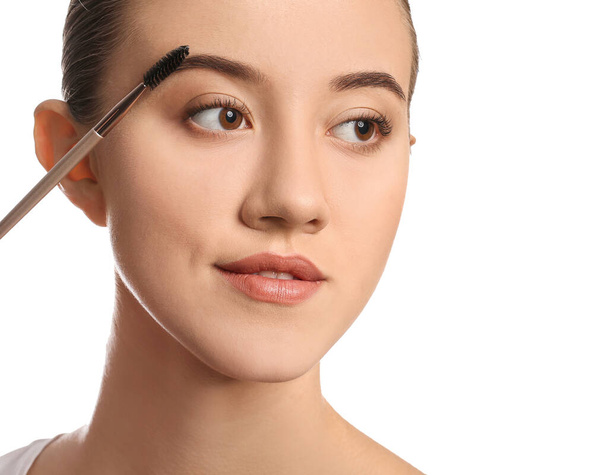 Young woman undergoing eyebrow correction procedure on white background - 写真・画像