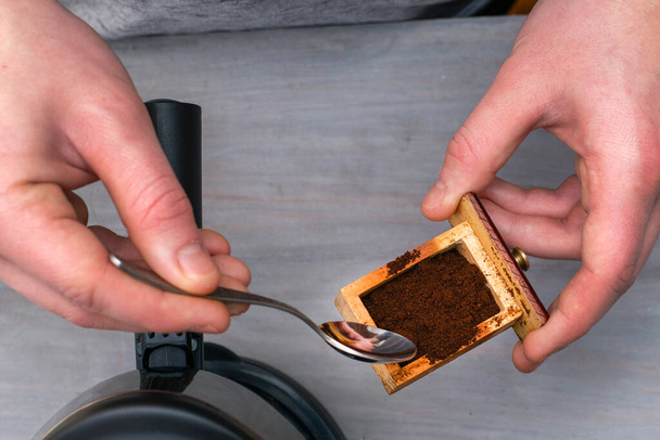 Kahve makinesinde kahve yapan biri kahve öğütücüsünden kaşıkla öğütülmüş kahve alır. Yüksek kalite fotoğraf - Fotoğraf, Görsel