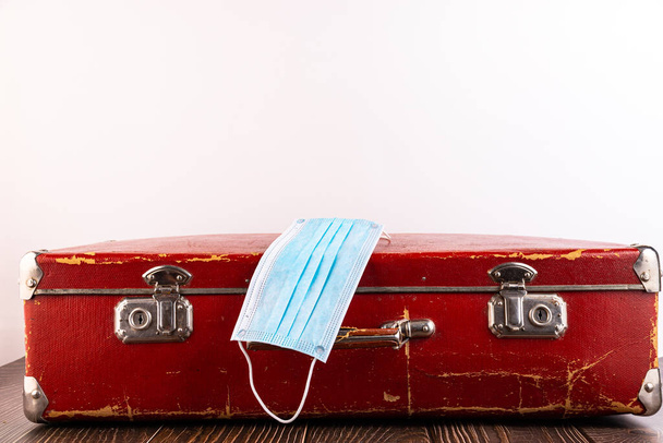 Close-up - a medical disposable mask is lying on a suitcase as an unsuccessful journey. Concept. - Photo, image