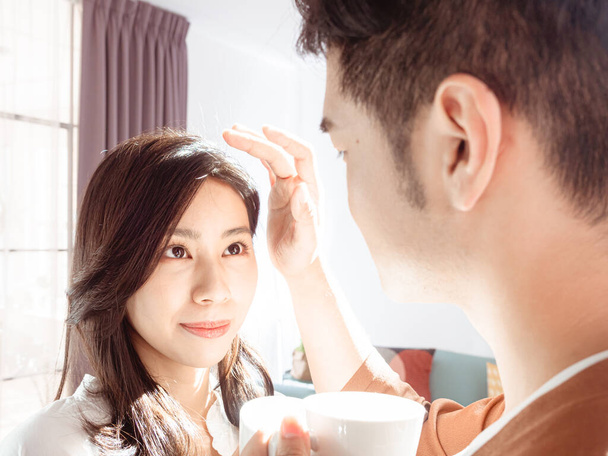 Femme asiatique et l'homme aiment passer du temps ensemble à la maison avec du café sous la lumière du soleil. - Photo, image